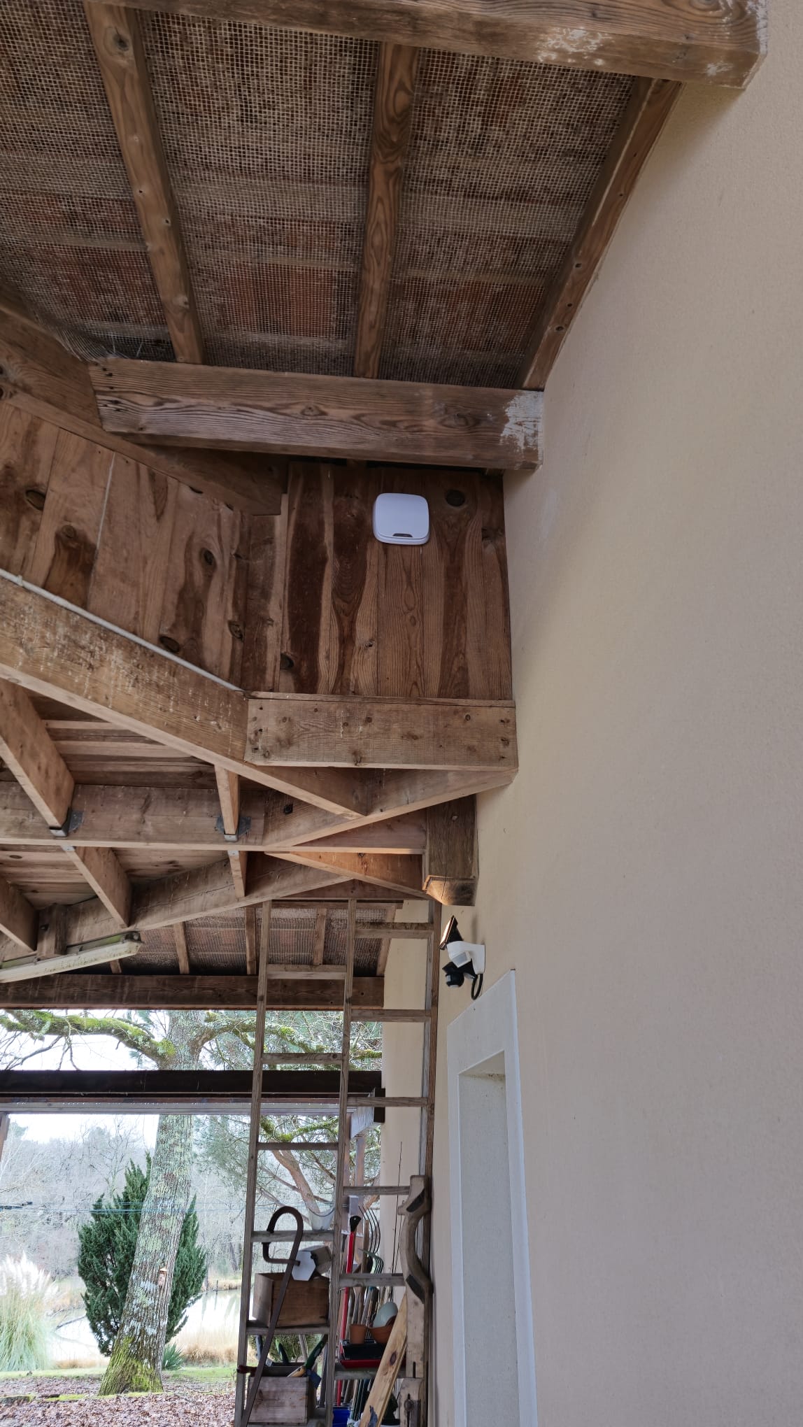 Installation Caméra Sécurité et Maison Intelligente Technicien installant une caméra de sécurité dôme au plafond tout en gérant le système de maison intelligente avec un smartphone affichant un code de verrouillage.