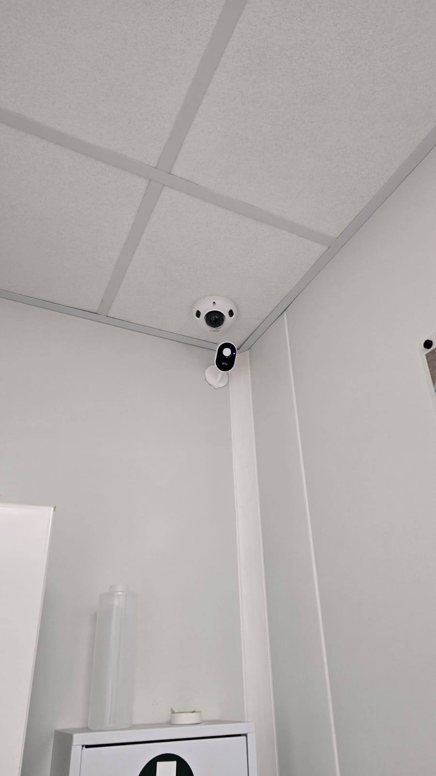 Installation Caméra Sécurité et Maison Intelligente Technicien installant une caméra de sécurité dôme au plafond tout en gérant le système de maison intelligente avec un smartphone affichant un code de verrouillage.