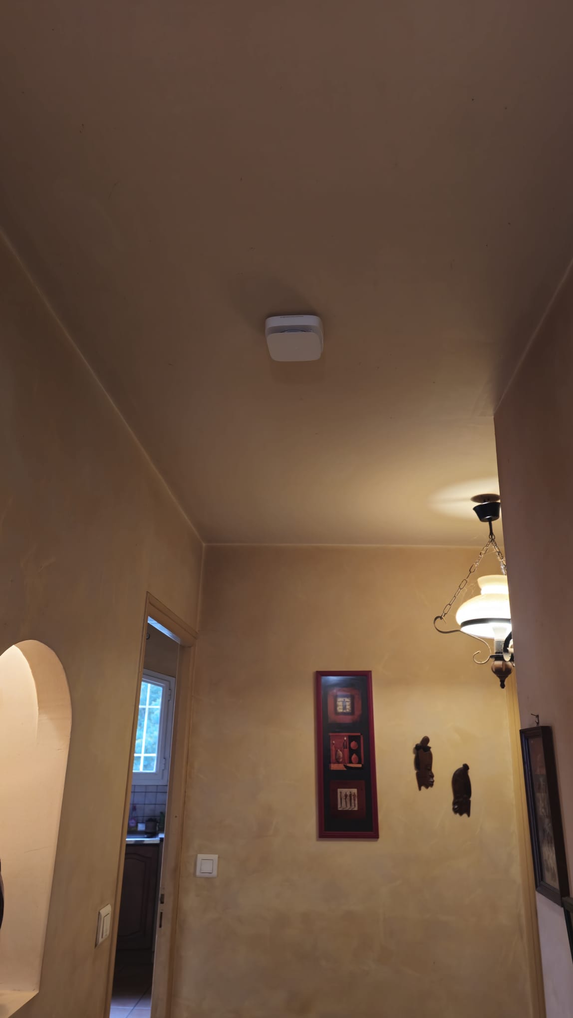 Installation Caméra Sécurité et Maison Intelligente Technicien installant une caméra de sécurité dôme au plafond tout en gérant le système de maison intelligente avec un smartphone affichant un code de verrouillage.