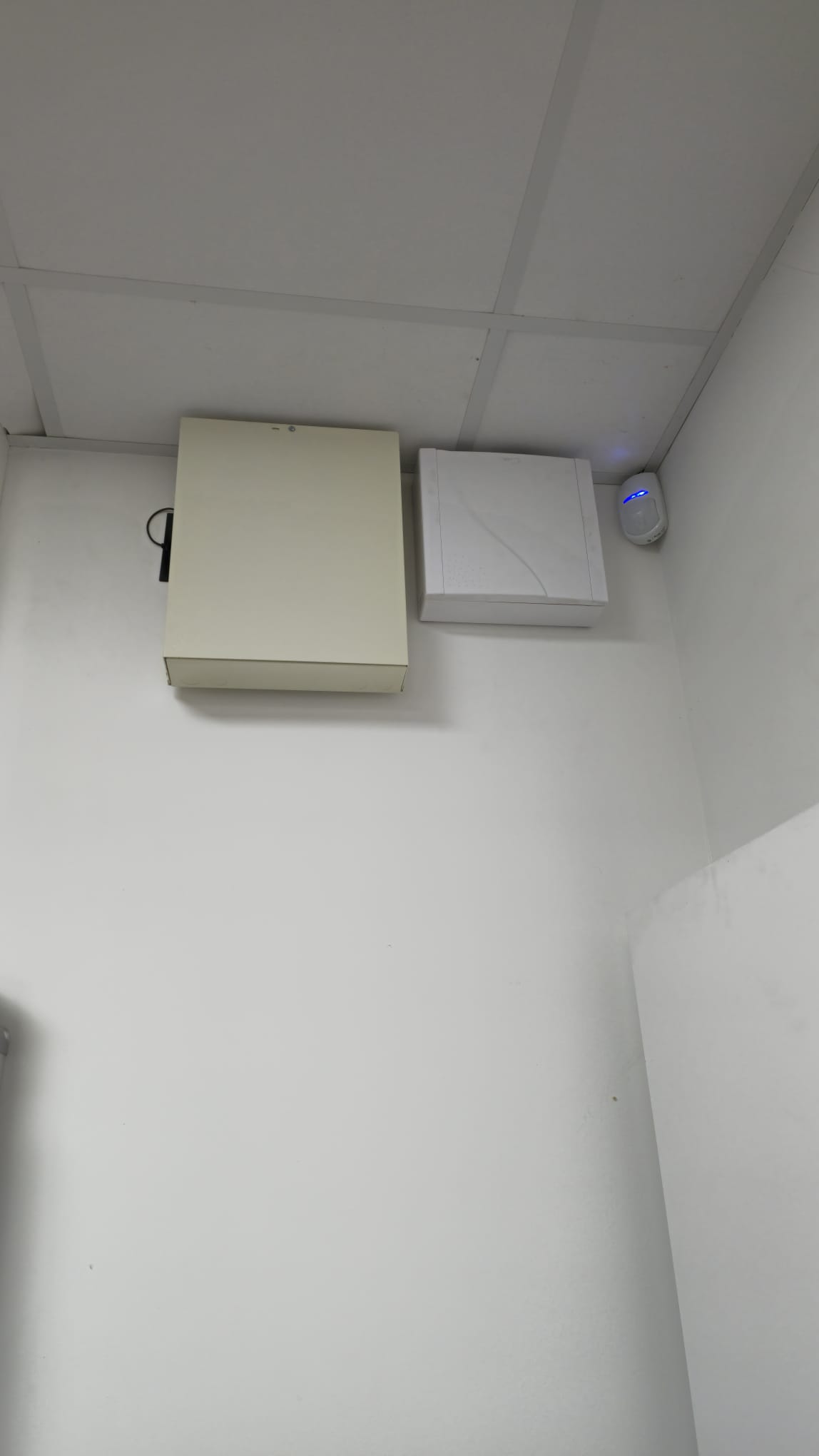 Installation Caméra Sécurité et Maison Intelligente Technicien installant une caméra de sécurité dôme au plafond tout en gérant le système de maison intelligente avec un smartphone affichant un code de verrouillage.