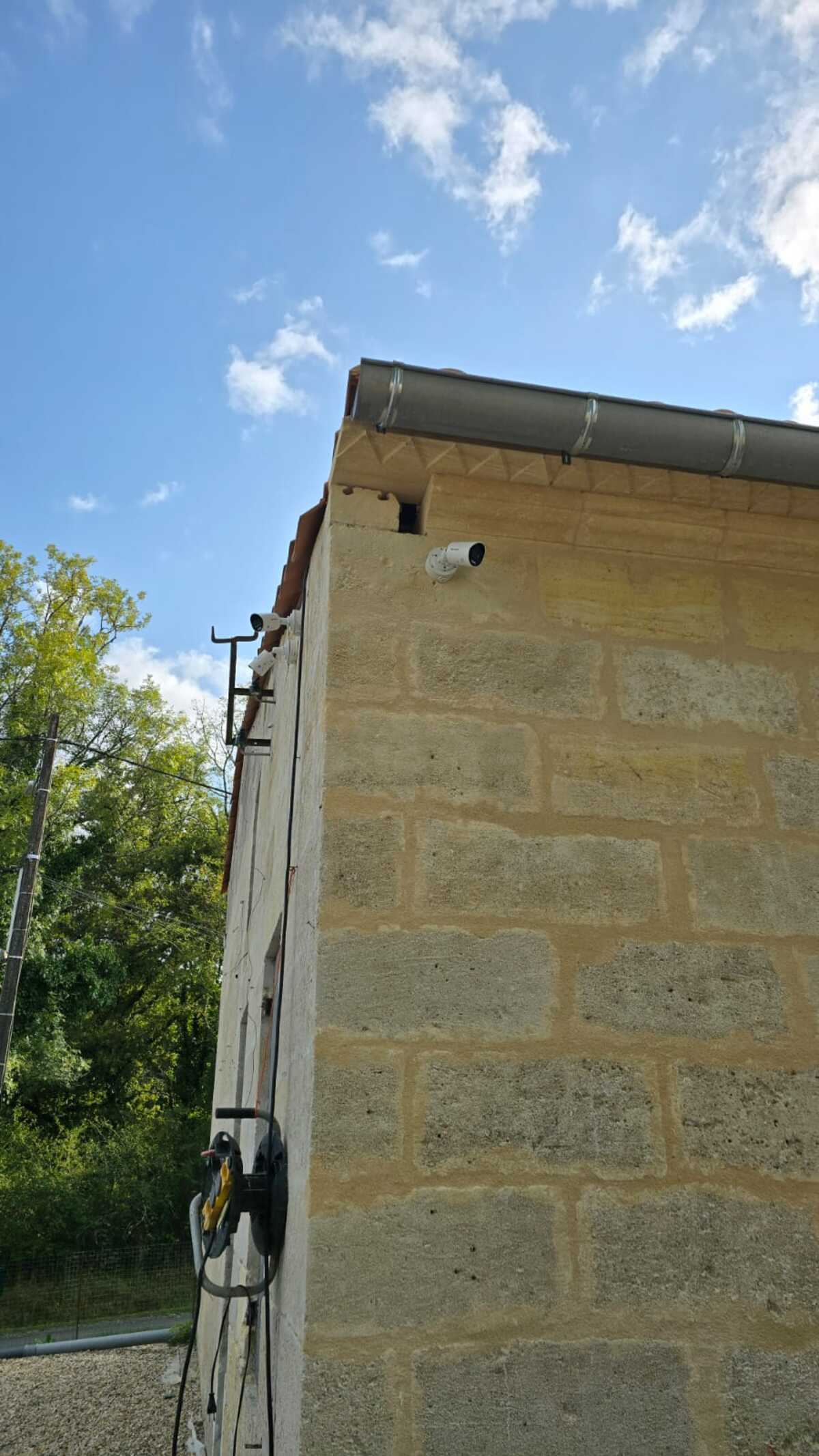 Installation Caméra Sécurité et Maison Intelligente Technicien installant une caméra de sécurité dôme au plafond tout en gérant le système de maison intelligente avec un smartphone affichant un code de verrouillage.