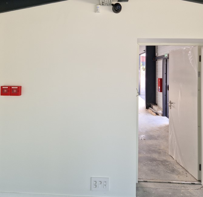 Installation Caméra Sécurité et Maison Intelligente Technicien installant une caméra de sécurité dôme au plafond tout en gérant le système de maison intelligente avec un smartphone affichant un code de verrouillage.