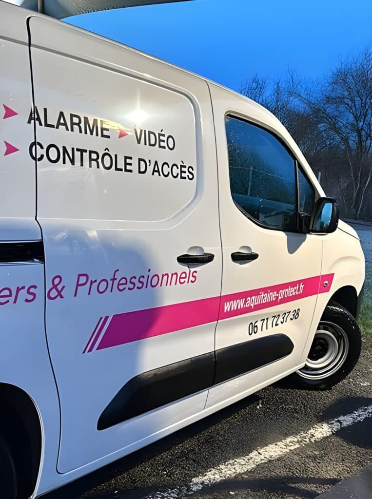 Alarme Vidéo - Contrôle d'Accès Aquitaine Protect Partie latérale d'un utilitaire blanc avec lettrage rose et noir : ALARME VIDÉO CONTRÔLE D'ACCÈS, aquitaine-protect.fr, 06 71 72 37 38.